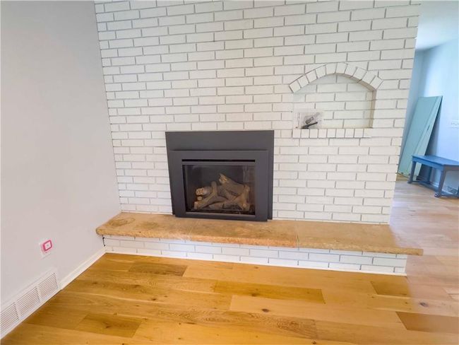 Room details with baseboards, wood finished floors, a fireplace, and visible vents | Image 17
