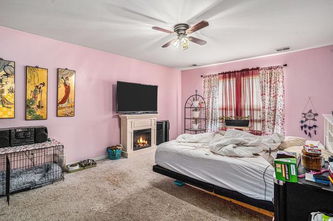 Bedroom featuring carpet flooring, ceiling fan, a warm lit fireplace, and baseboards | Image 14