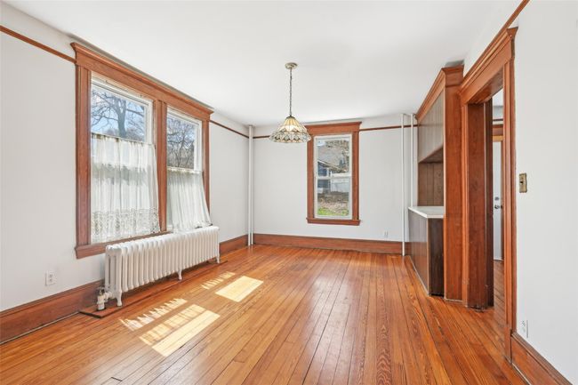 Spare room with a wealth of natural light, hardwood / wood-style flooring, an inviting chandelier, and radiator | Image 8