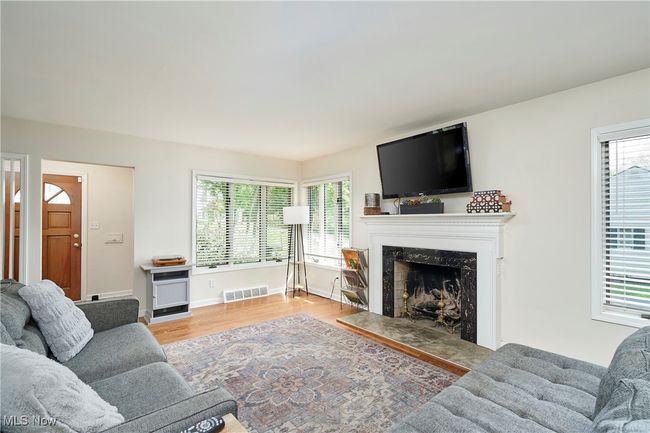 Living room featuring a premium fireplace, healthy amount of natural light, wood finished floors, and baseboards | Image 9