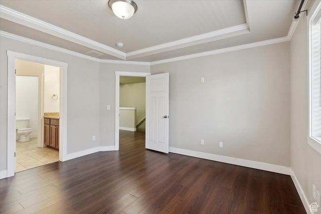 Empty room with wood finished floors, baseboards, ornamental molding, and a raised ceiling | Image 15