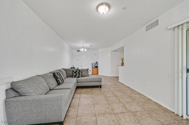 Living area with light tile patterned floors and a chandelier | Image 4