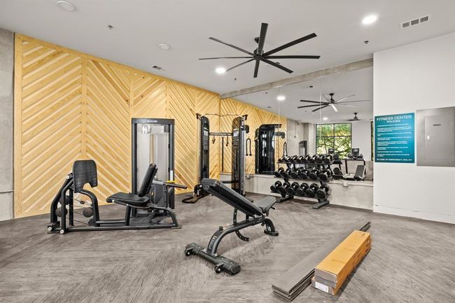 Exercise area featuring a ceiling fan and wood walls | Image 25