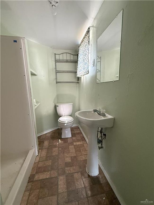 Bathroom with toilet, baseboards, and brick floor | Image 8