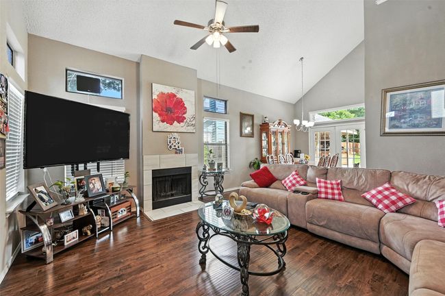 Living room featuring a ceiling fan, wood finished floors, high vaulted ceiling, and a fireplace | Image 11
