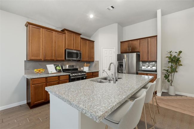 This kitchen is by far any chef’s dream! This lovley kitchen features dark stained wood cabinets, granite countertops, SS appliances, modern tile backsplash, recessed lighting, granite kitchen island with sink and space for breakfast bar all overlooking the living room. *Virtually Staged | Image 8