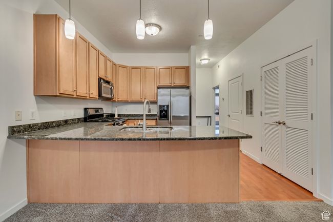Kitchen with a sink, appliances with stainless steel finishes, a peninsula, visible vents, and dark stone counters | Image 9