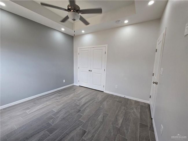 Unfurnished bedroom featuring recessed lighting, dark wood-style floors, baseboards, ceiling fan, and a closet | Image 14