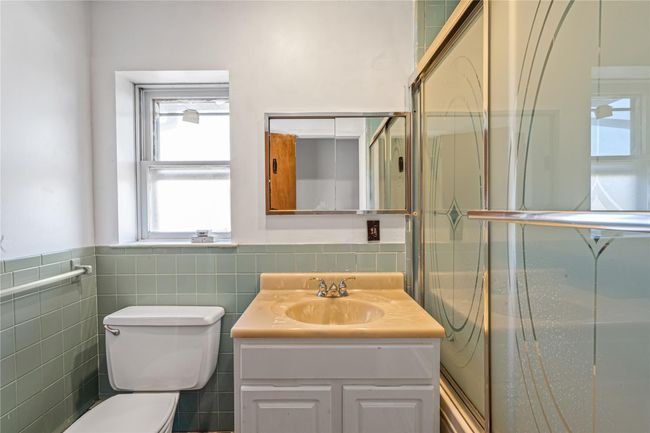 Bathroom featuring toilet, vanity, a wainscoted wall, and tile walls | Image 18