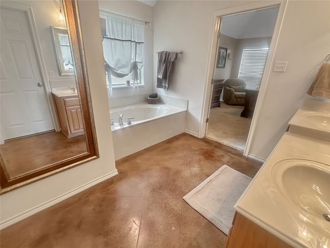Bathroom with double vanity, a garden tub, tile patterned floors, and baseboards | Image 10