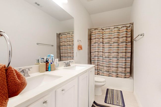 Bathroom with toilet, shower / bath combo with shower curtain, a sink, and tile patterned flooring | Image 28