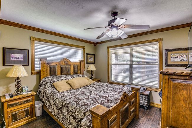 Bedroom with dark wood-style floors, ornamental molding, a textured ceiling, and a ceiling fan | Image 22