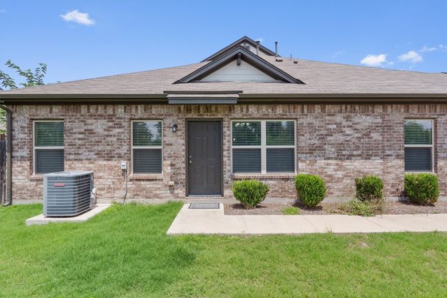 View of front of home with central AC, a shingled roof, a front lawn, and brick siding | Image 4
