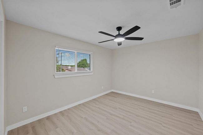 Empty room with baseboards, visible vents, wood finished floors, and a ceiling fan | Image 18