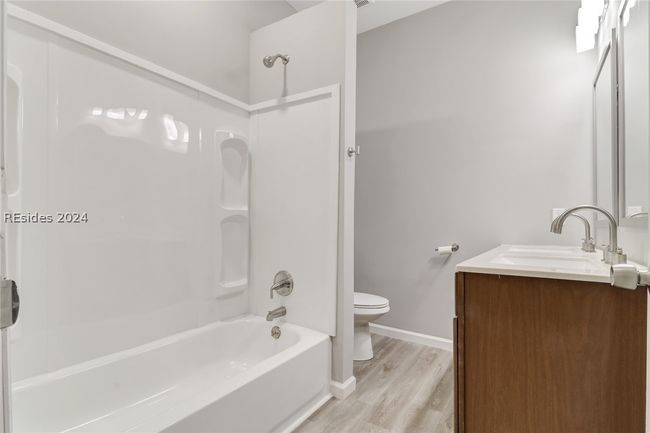 Full bathroom featuring washtub / shower combination, hardwood / wood-style flooring, toilet, and vanity | Image 26