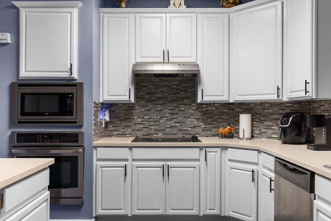 Kitchen with decorative backsplash, stainless steel appliances, and white cabinets | Image 15