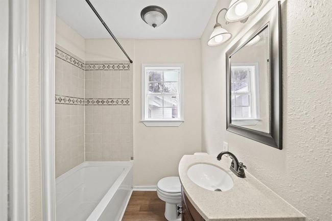 This gorgeous Primary Bathroom is complete with a large garden style tub and lovely tile walls, a framed mirror, vinyl plank floors and granite countertops. | Image 13