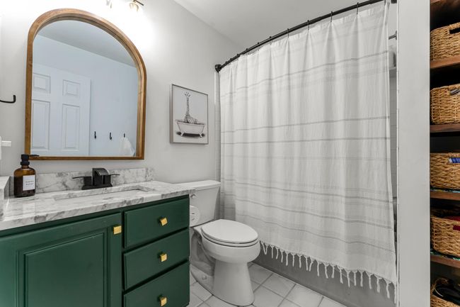 Both bedrooms enjoy easy access to a shared full bathroom with a tiled tub/shower combo and built-in shelving for added organization. | Image 18