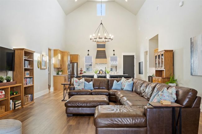 Living area featuring a chandelier, high vaulted ceiling, wood finished floors, and baseboards | Image 5