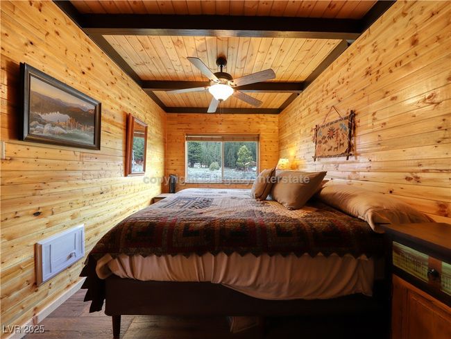 Bedroom featuring beamed ceiling, wood walls, wooden ceiling, and visible vents | Image 17