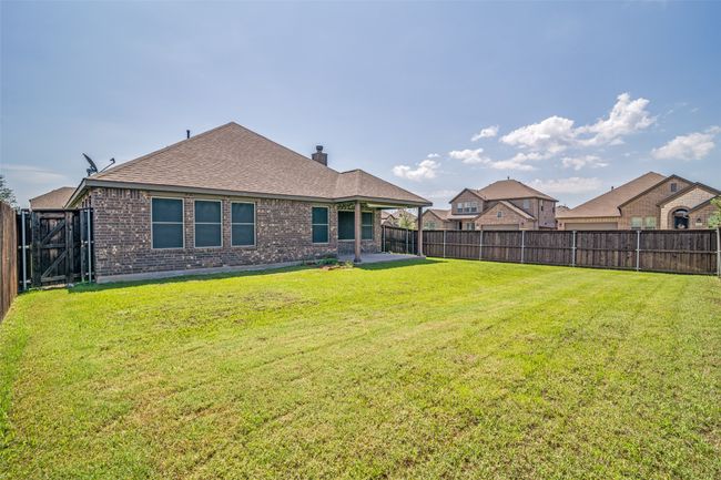 Rear view of house featuring a fenced backyard, brick siding, a patio area, a shingled roof, and a chimney | Image 24