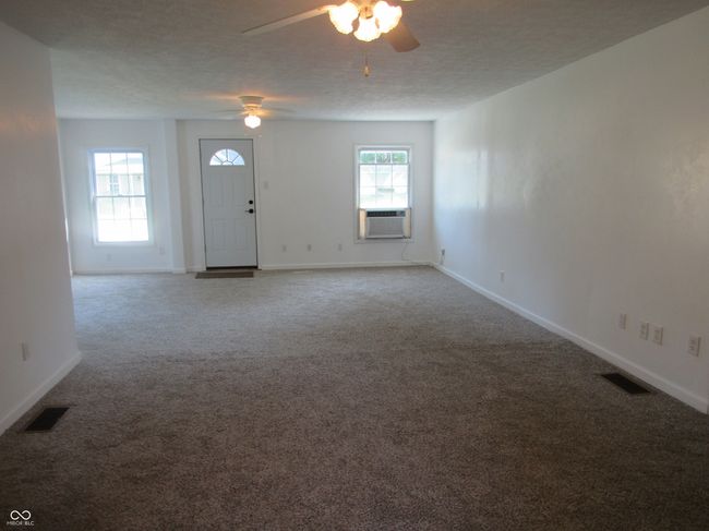 unfurnished living room featuring a ceiling fan and carpet | Image 6