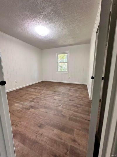 Spare room with dark wood-type flooring and a textured ceiling | Image 2