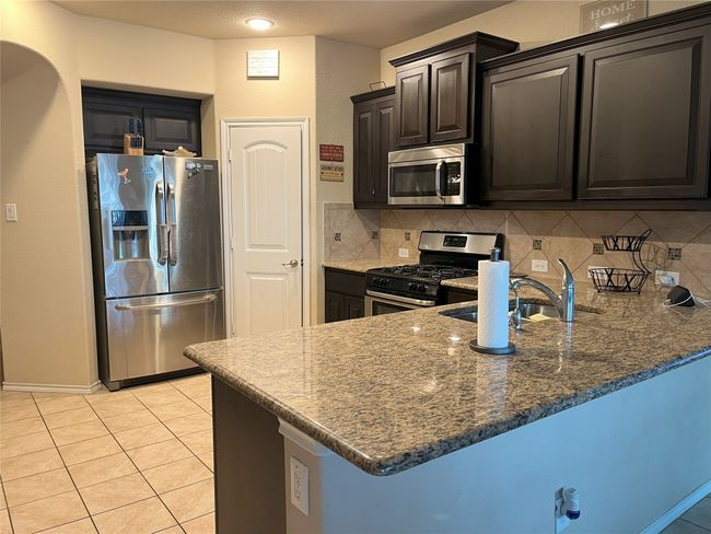 Kitchen with sink, appliances with stainless steel finishes, dark stone countertops, decorative backsplash, and kitchen peninsula | Image 6