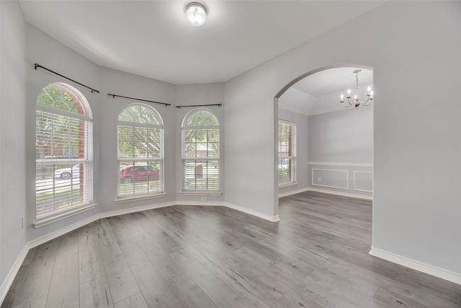 Spare room with arched walkways, a chandelier, wood finished floors, and wainscoting | Image 10