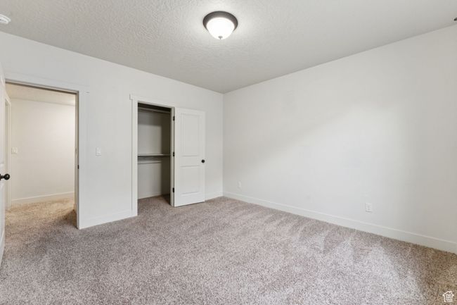 Unfurnished bedroom featuring carpet flooring, baseboards, a textured ceiling, and a closet | Image 16