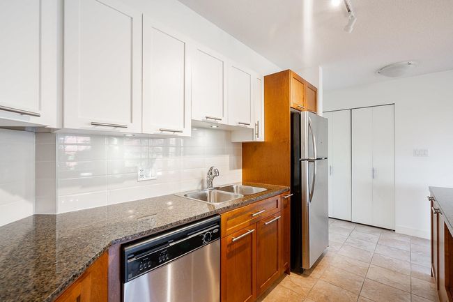 Kitchen with tasteful backsplash, brown cabinetry, appliances with stainless steel finishes, white cabinets, and a sink | Image 4