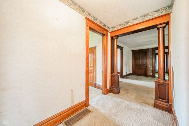 corridor with ornate columns, a textured ceiling, visible vents, carpet floors, and baseboards | Image 7