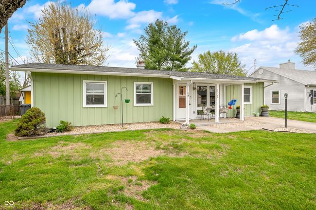 back of house featuring board and batten siding, a chimney, fence, and a yard | Image 4