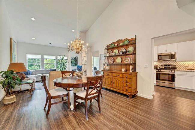 Dining space featuring a chandelier, high vaulted ceiling, wood finished floors, and recessed lighting | Image 4
