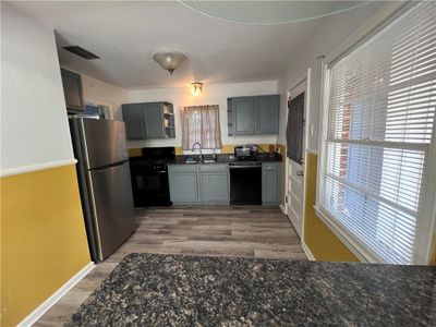 Kitchen featuring hardwood / wood-style floors, sink, black appliances, and gray cabinetry | Image 3