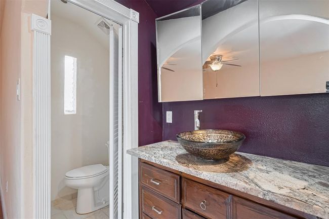 4th bath upstairs with stylish vessel sink and granite vanity features rich-toned cabinetry and a custom mirror cabinet, offering both form and function. | Image 42