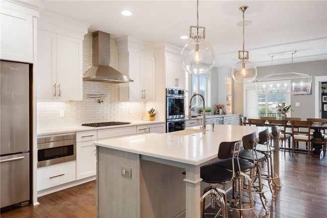 Jenn Air stainless steel appliances include 6 burner gas cook top, double oven, large center island with quartz counter top and seating. | Image 9