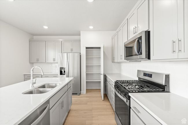 Kitchen with stainless steel appliances, light wood-style flooring, decorative backsplash, recessed lighting, and gray cabinetry | Image 24
