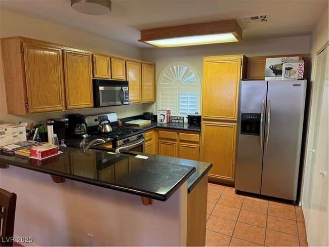Kitchen with range, dark countertops, visible vents, a peninsula, and refrigerator | Image 4