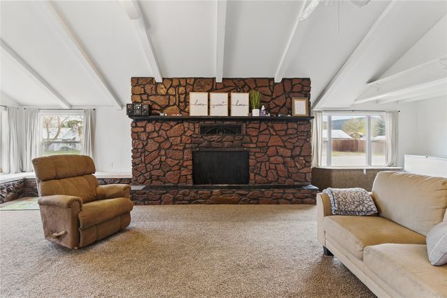 Living area featuring lofted ceiling with beams, a healthy amount of sunlight, carpet flooring, and a fireplace | Image 9