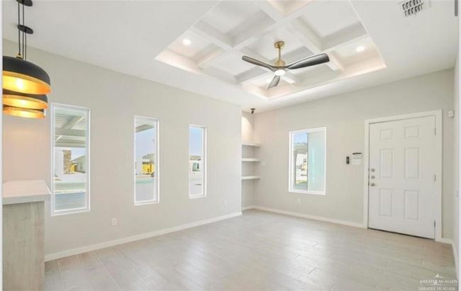 Empty room with light hardwood / wood-style floors, coffered ceiling, beam ceiling, and ceiling fan | Image 5