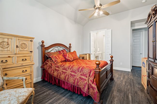 Bedroom with ceiling fan, ensuite bathroom, dark hardwood / wood-style floors, and vaulted ceiling | Image 16