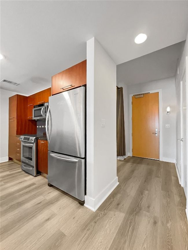 Kitchen with appliances with stainless steel finishes, light wood-style floors, modern cabinets, baseboards, and brown cabinets | Image 8