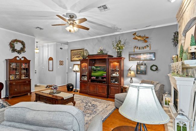 Living room with crown molding, ceiling fan, and light wood-type flooring | Image 7