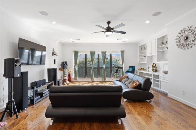 Another view of the secondary living area, highlighting the built-in storage, ceiling fan, and large windows that fill the space with natural light, making it both functional and inviting. | Image 29