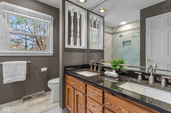 Hall bath has 2 sinks, granite counter, tile tub/shower with frameless door | Image 32