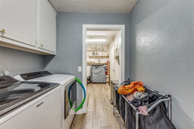 Laundry area featuring cabinet space, washer and dryer, light wood finished floors, and a textured wall | Image 22