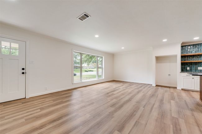 Unfurnished living room featuring, light wood-style flooring, recessed lighting, and bar area | Image 6
