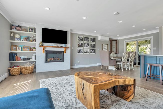 Living room with crown molding, a large fireplace, a wall mounted AC, and wood finished floors | Image 14