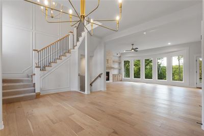 Unfurnished living room with ceiling fan with notable chandelier and light hardwood / wood-style flooring | Image 3